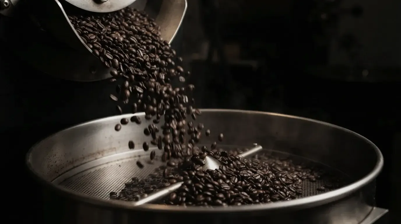 Macro photograph of dark roasted coffee beans falling into a cooling tray